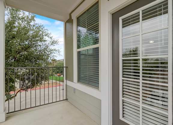 A balcony with a white railing and a window with white blinds.
