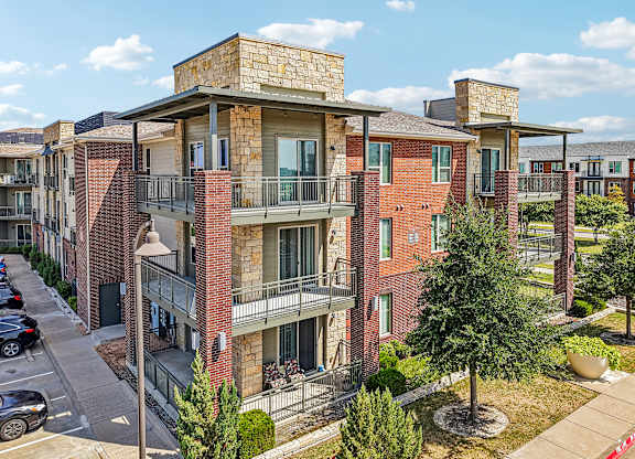 Apartment complex with red brick buildings and green trees.