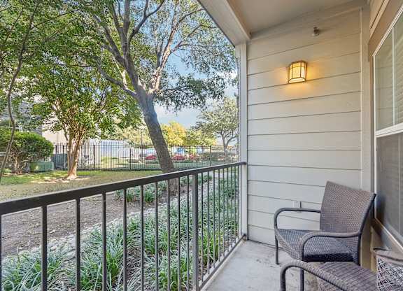 A balcony with a chair and a lamp on the wall.
