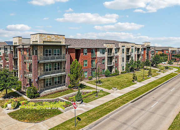 A road with a stop sign in front of apartment buildings.
