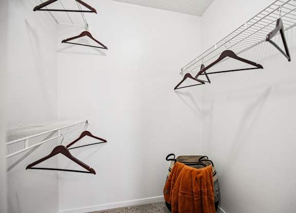 A white wall with clothes hangers and a bag.