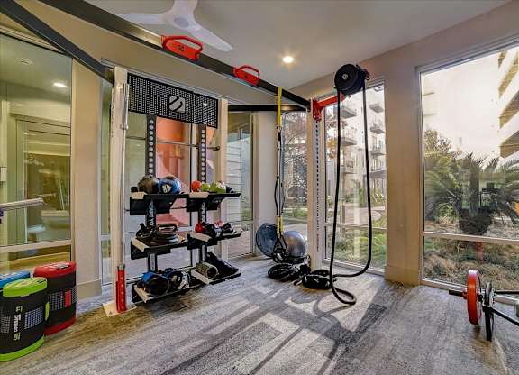 A gym room with a variety of equipment including a treadmill, weights, and a fan.