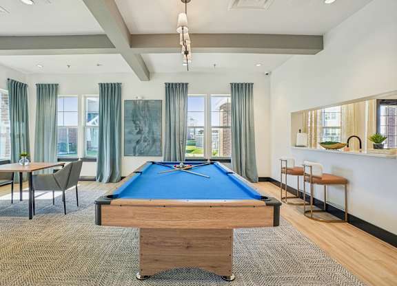 A room with a pool table and a bar area.