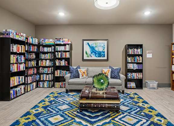 A living room with a couch, a coffee table, and bookshelves filled with books.