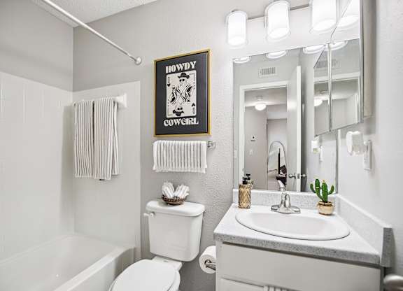 A bathroom with a white toilet, sink, and a poster on the wall.