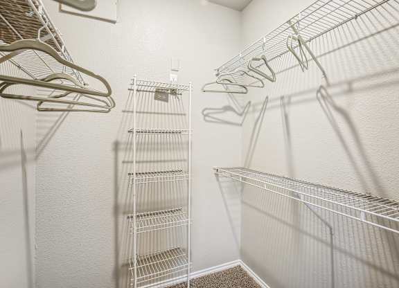 A white closet with metal racks and hangers.