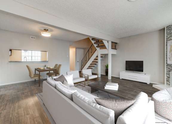 A living room with a grey sofa and a wooden staircase.