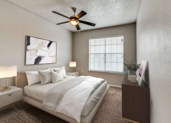 A bedroom with a bed, nightstands, and a ceiling fan.