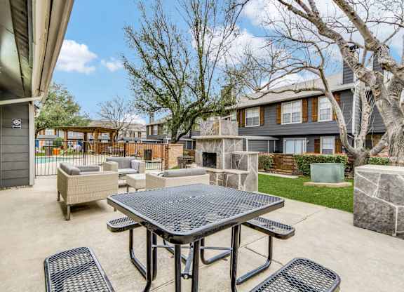 A patio with a table and chairs is surrounded by trees and houses.