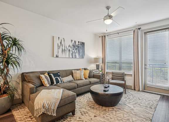 A living room with a brown couch and a painting on the wall.
