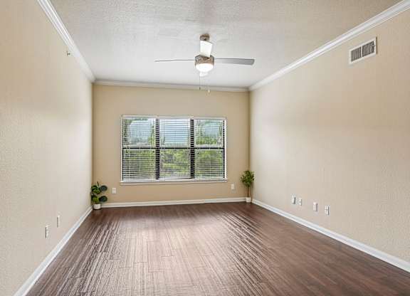 A room with a ceiling fan and a window with blinds.