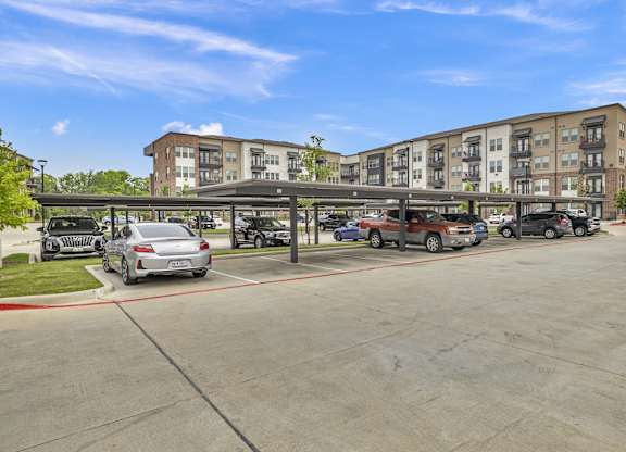 an empty parking lot with cars in front of an apartment building