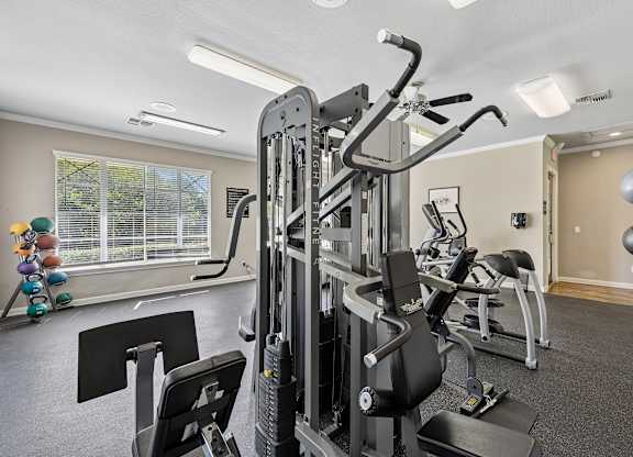 A gym with a variety of equipment including a treadmill, weights, and a bench press.