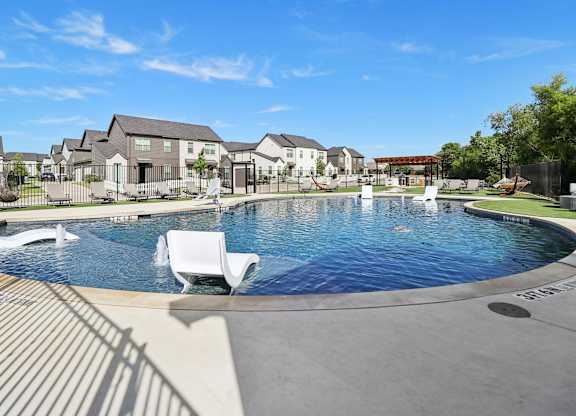 A swimming pool with a white lounge chair in the foreground.