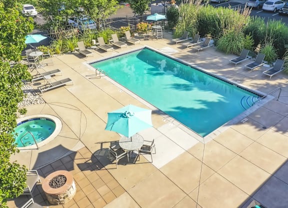 a swimming pool and patio with chairs and umbrellas