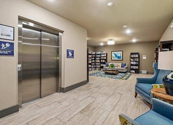 A hallway with a blue couch, a bookshelf, and a coffee table.