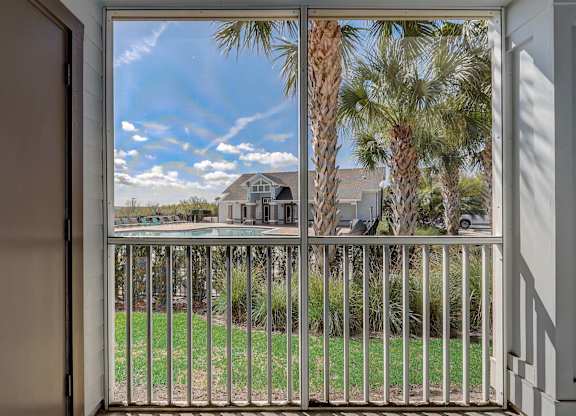 the view from the balcony of a house overlooking a pool and palm trees