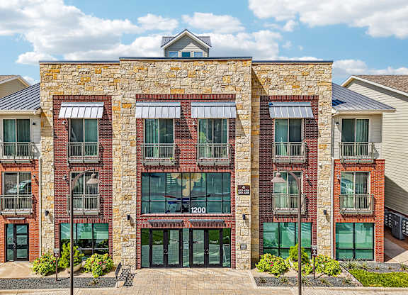 A building with a stone facade and a balcony with a black railing.