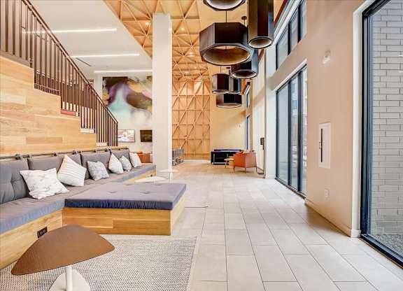 Hallway lounge with built-in bench seating, oversized pendant lights, and tall windows.