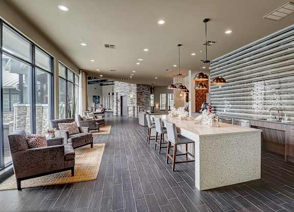 a large kitchen with a long counter with chairs and a table