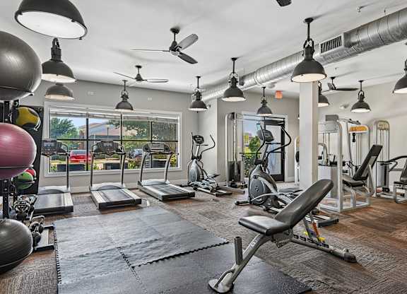 A gym with a variety of equipment including treadmills, weights, and exercise machines.