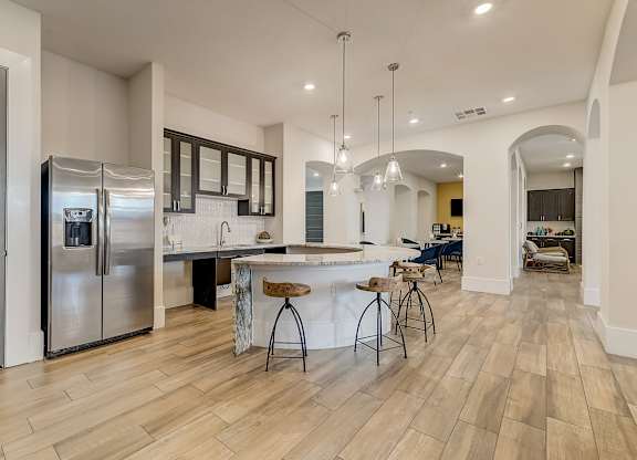 A kitchen with a bar and stools in the middle of the room.