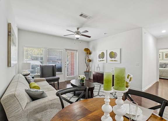 A living room with a grey couch, a wooden table, and a ceiling fan.