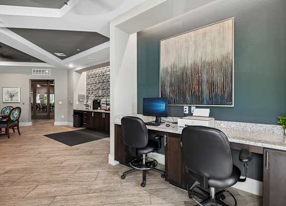 A modern home office with a desk, chairs, and a large abstract painting on the wall.
