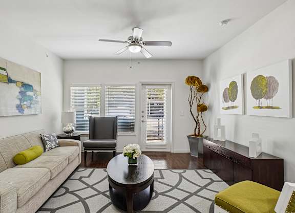 A living room with a beige couch, a coffee table, and a ceiling fan.