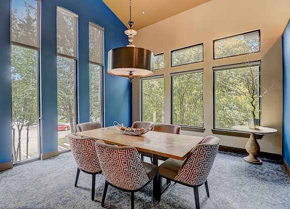 a dining room with a table and chairs and large windows