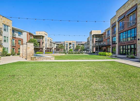A sunny day in a residential area with a grassy lawn and apartment buildings.