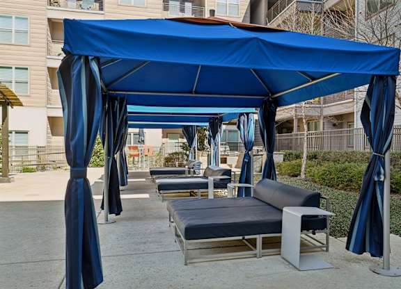 A blue canopy with curtains and a bench underneath it.