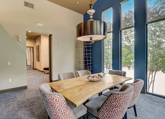 a dining room with a wooden table and chairs and large windows