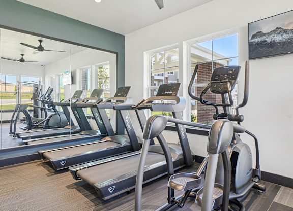 A gym with treadmills and a fan.