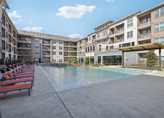 A large swimming pool is surrounded by apartment buildings.