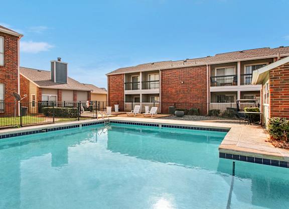 A swimming pool in front of a brick building with a clear blue sky.