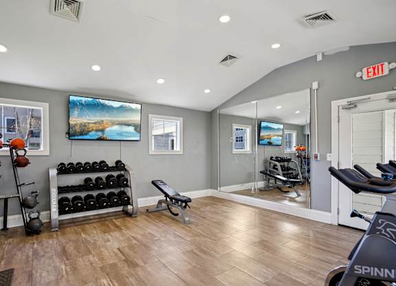 A gym with a Spinn bike and a row of dumbbells.