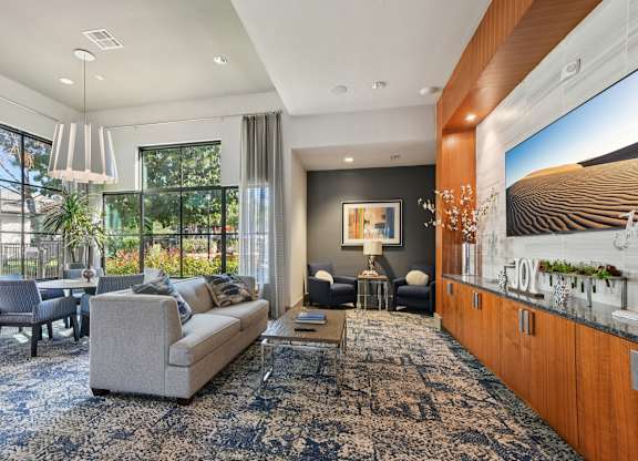 A living room with a grey sofa and a large painting on the wall.