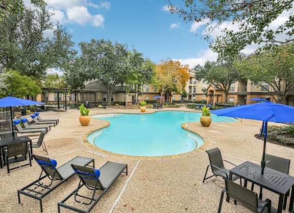 A pool surrounded by chairs and umbrellas in a sunny day.