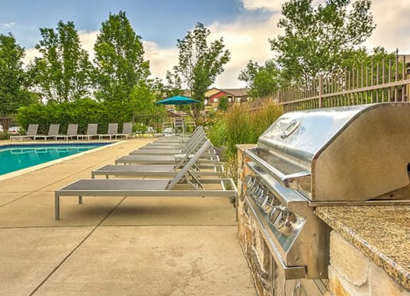 A row of sun loungers are lined up by a pool.