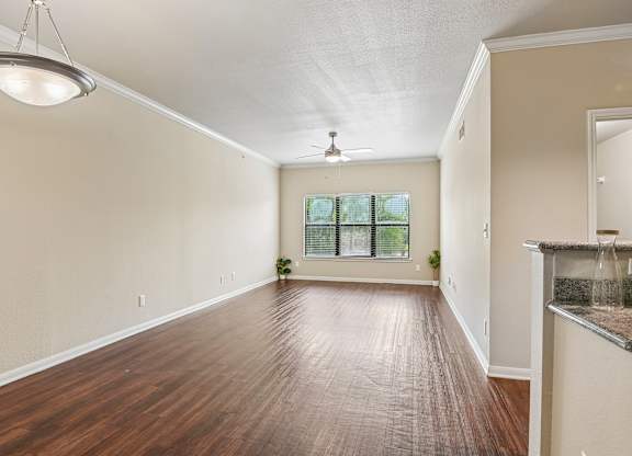 A spacious room with wooden floors and a ceiling fan.