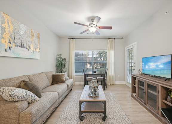 A living room with a couch, a coffee table, a television, and a painting on the wall.
