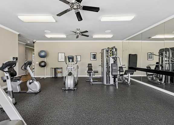 A spacious gym with a variety of equipment including treadmills, stationary bikes, and weight machines.