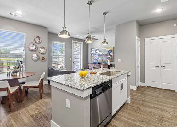 A kitchen with a large island and a dining table with chairs.