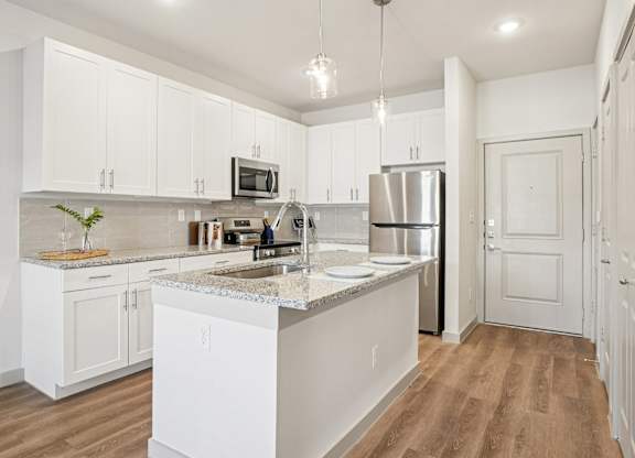 A kitchen with white cabinets and a marble countertop.