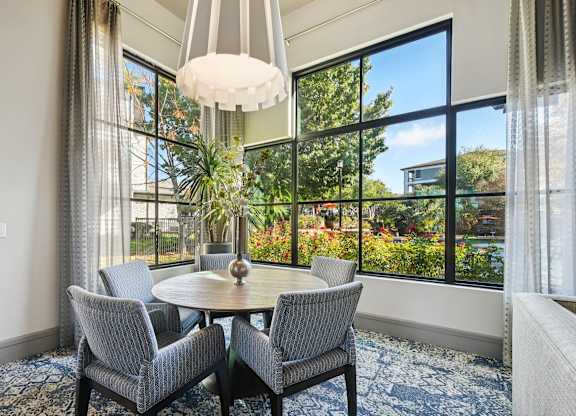 A dining room with a round table and grey chairs.