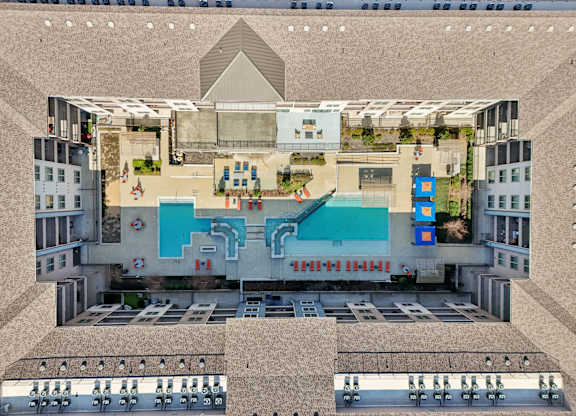 A top-down view of a building with a pool and a large open area with people sitting on chairs.