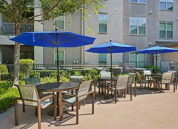 A patio with tables and chairs and umbrellas.