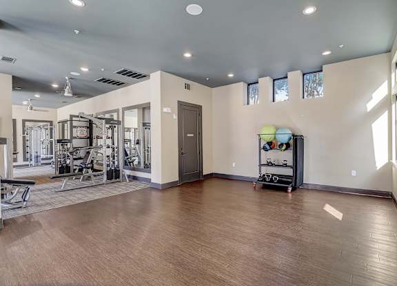 a workout room with a treadmill and weights on a wooden floor