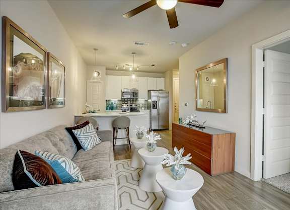 Open-concept living area leading to kitchen, with sofa seating and modern wall art.